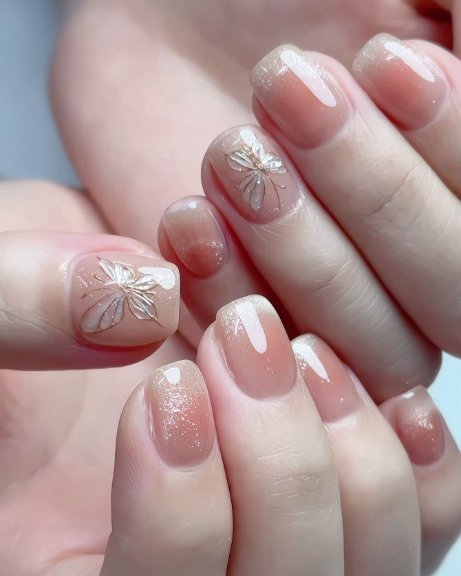 Elegant short nude bridal nails with shimmer and white floral accents – wedding-ready style