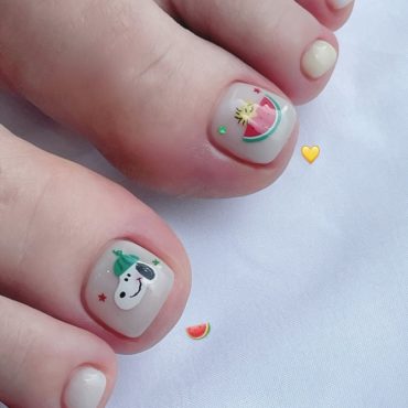 Toe nails with white polish featuring Snoopy and watermelon cartoon art on big toes in a cute summer style