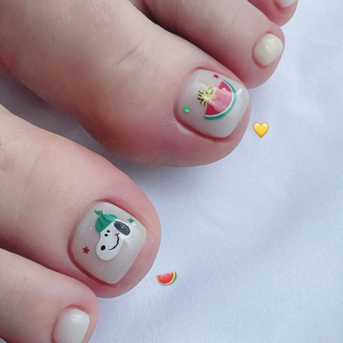 Toe nails with white polish featuring Snoopy and watermelon cartoon art on big toes in a cute summer style