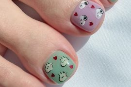 Toe nails in pastel green and lavender featuring Snoopy faces and small red hearts on short square nail shapes