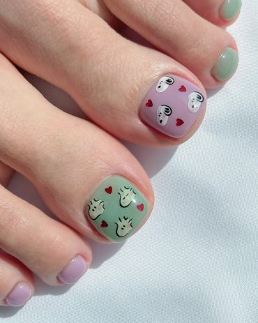 Toe nails in pastel green and lavender featuring Snoopy faces and small red hearts on short square nail shapes