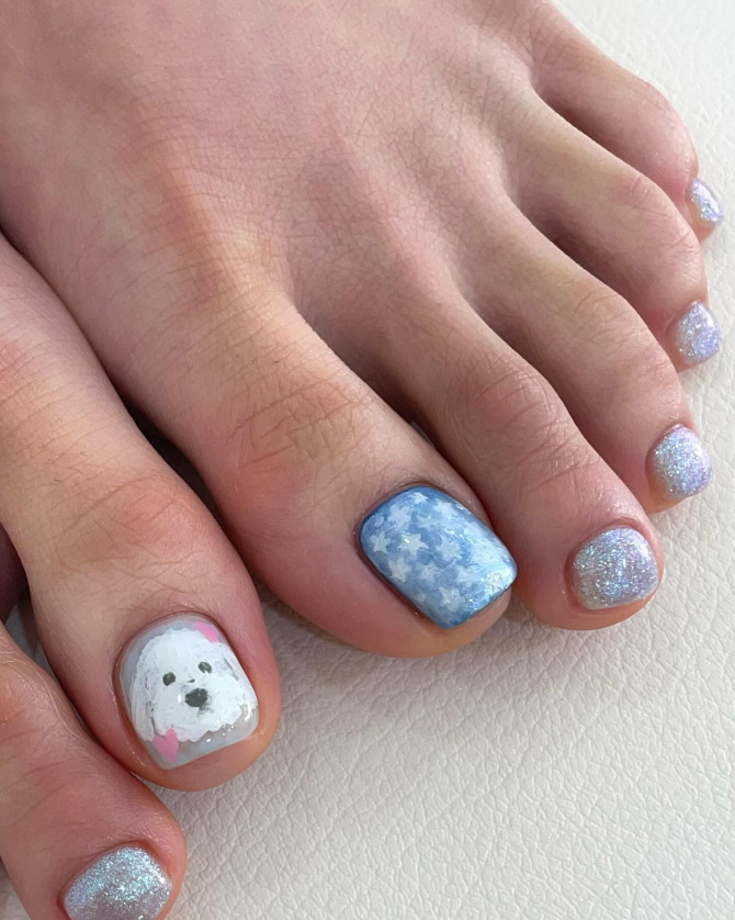 Toe nails with hand-painted white puppy, blue star background, and silver-blue glitter polish on short square nails