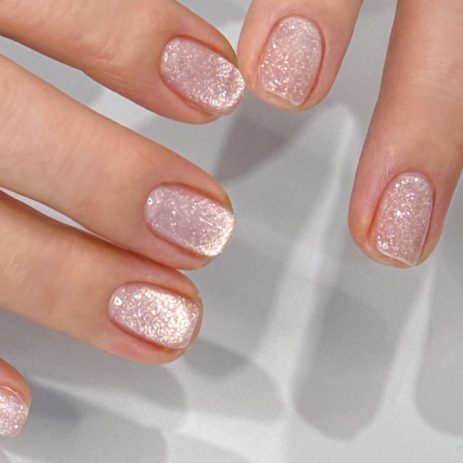Short natural nails with fine textured pink glitter and soft crystal-like shimmer.