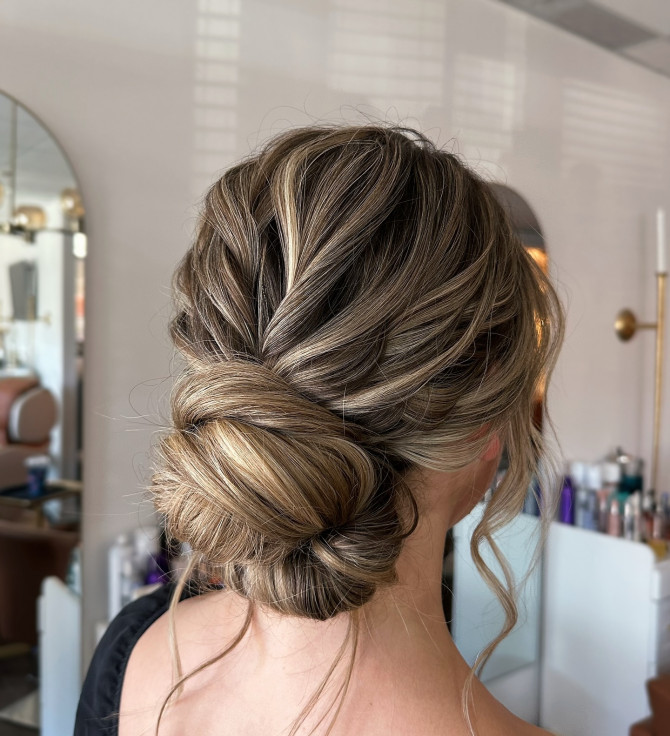  Soft, textured low bridal bun with beige blonde highlights.