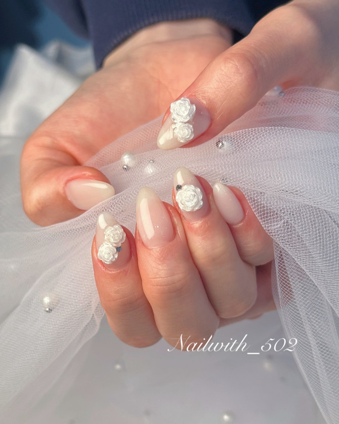These dreamy bridal nails showcase the beauty of simplicity with a luxurious 3D floral twist. Set on a soft ombré nude and white base, the look is elevated with hand-sculpted white rose embellishments that exude classic bridal charm. Each petal is finely detailed, giving the design a dimensional feel while remaining light and graceful. This manicure is ideal for traditional ceremonies, bridal portraits, or romantic garden weddings. The balance between the minimalist polish and statement florals creates a look that’s both timeless and modern. Whether paired with a lace gown or a sleek silhouette, these nails will enhance your bridal glow. Find more 3D bridal nail inspirations that celebrate elegance through texture, detail, and refined design. 