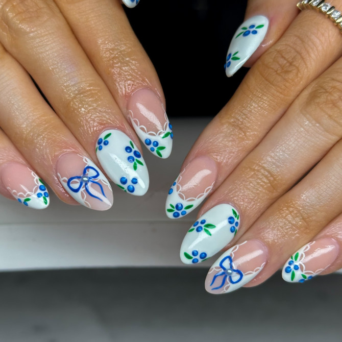  blueberry nail designs with white tips, lace accents, and blue bows on almond nails