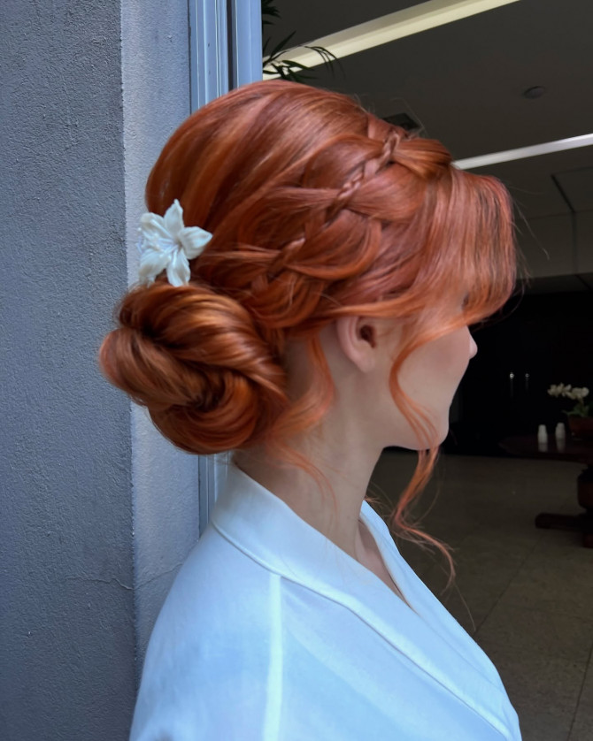 Side braided low bridal bun in soft tangerine red with white flower pin by @penteadoslucena