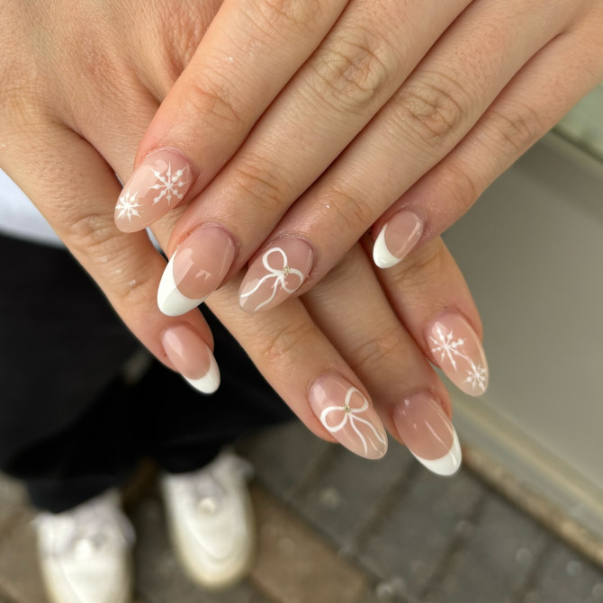 Elegant nude almond nails with classic white French tips and hand-painted white ribbons and florals—ideal for a timeless and romantic bridal look.