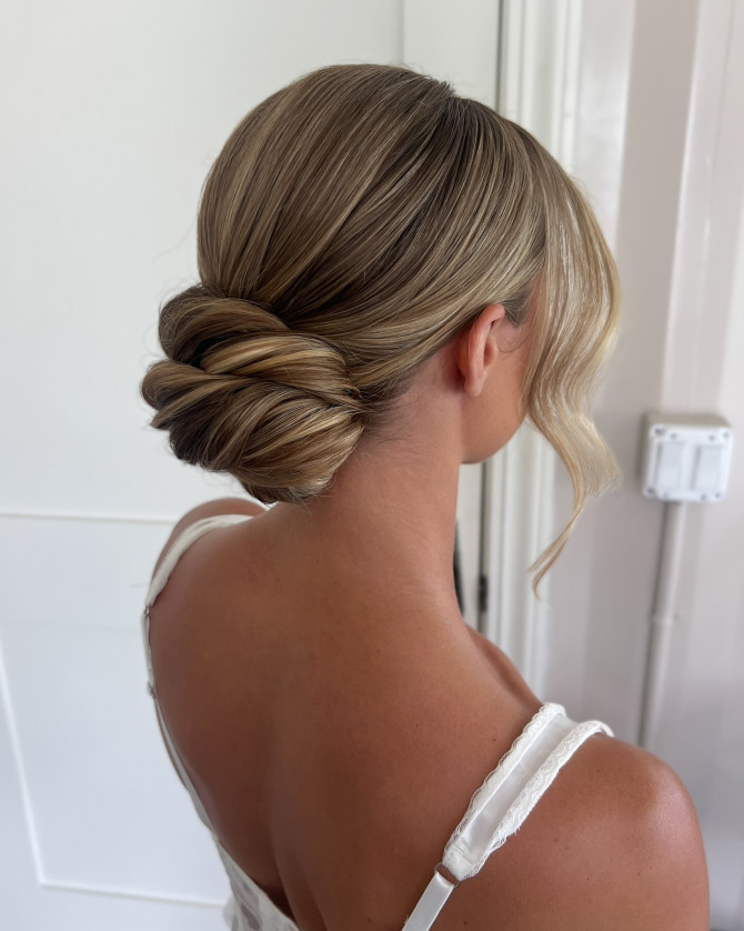 Sleek low bridal knot with side part and soft face-framing wave by @erikataftbridal