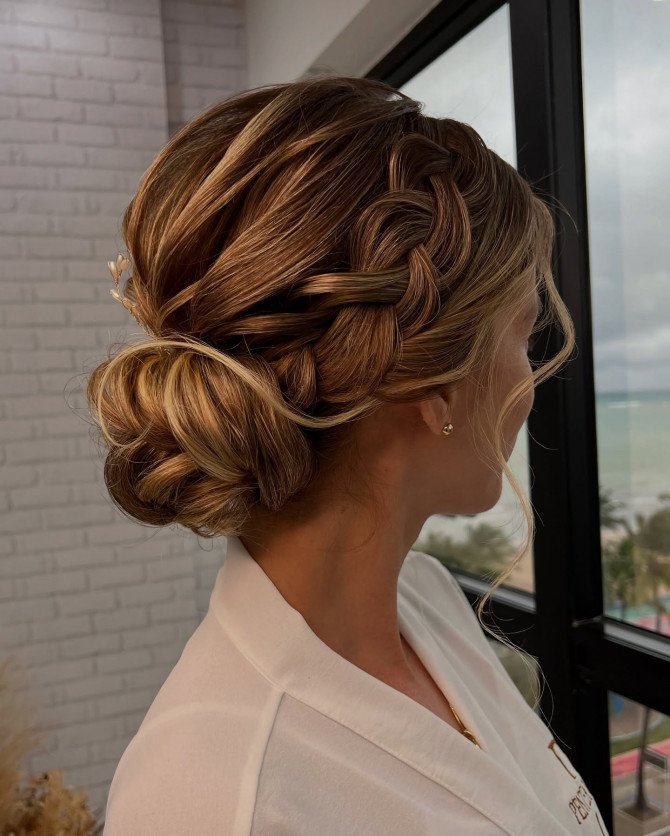 Romantic braided bridal low bun with soft golden highlights and loose curls by @penteadoslucena