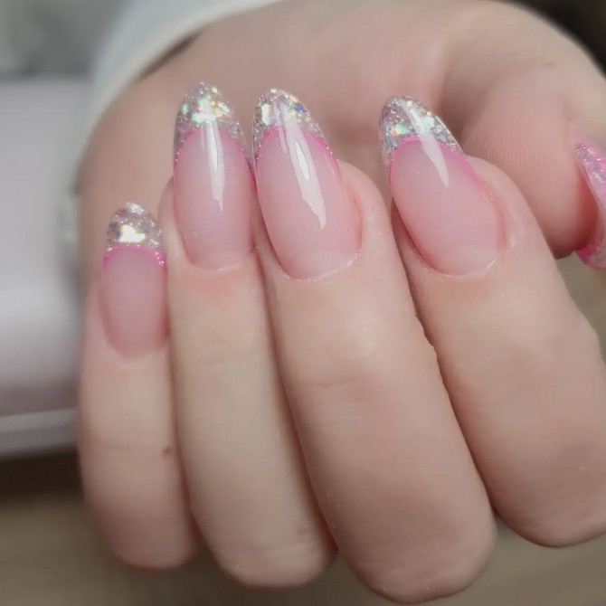Almond-shaped bridal nails with clear pink base, iridescent glitter French tips, and a soft pink outline—ideal for brides who love sparkle and glamour.