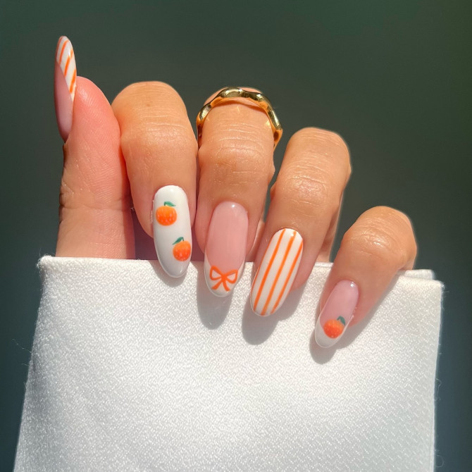 style nail art with orange fruit designs, stripes, and bow.