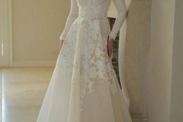 Elegant lace appliqué long-sleeve bridal gown by Zehavi Pick, featuring a high neckline and soft ivory silhouette.