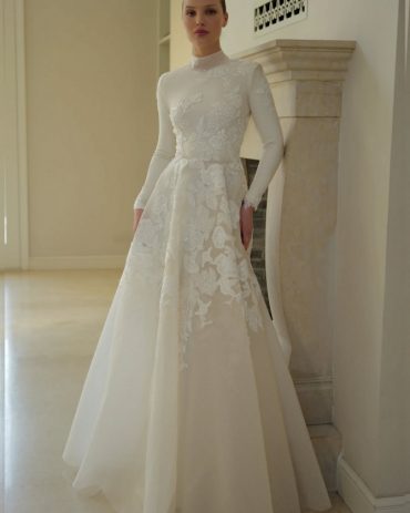 Elegant lace appliqué long-sleeve bridal gown by Zehavi Pick, featuring a high neckline and soft ivory silhouette.