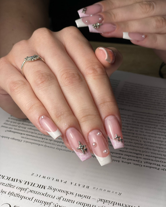Square pink French tip bridal nails with pearl accents, geometric white art, and 3D silver charms—ideal for fashion-forward brides seeking a creative and unique look.