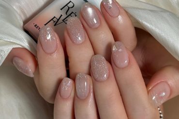 Nude base nails with fine glitter and soft shine overlay.