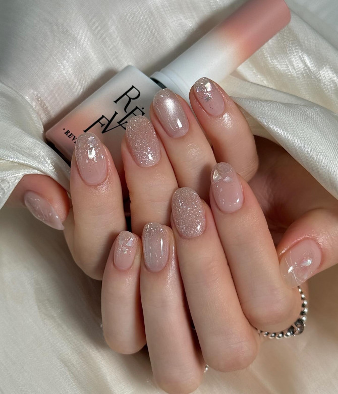 Nude base nails with fine glitter and soft shine overlay.
