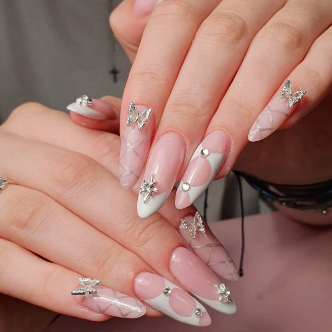 Long almond bridal nails in a pink and white design featuring silver rhinestones, crystal butterflies, and delicate diamond mesh patterns—perfect for a statement wedding manicure