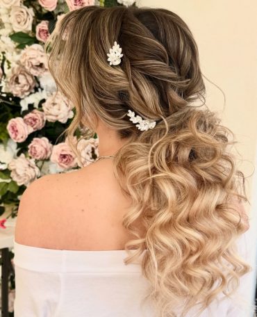 Romantic bridal ponytail hairstyle with soft curls and twisted details by @shannonsarabridalhair.
