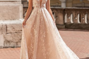 Bride wearing a deep V-neck A-line wedding dress with cap sleeves and floral lace by Leen Dias. One-shoulder cape bridal gown with unique neckline and bold style