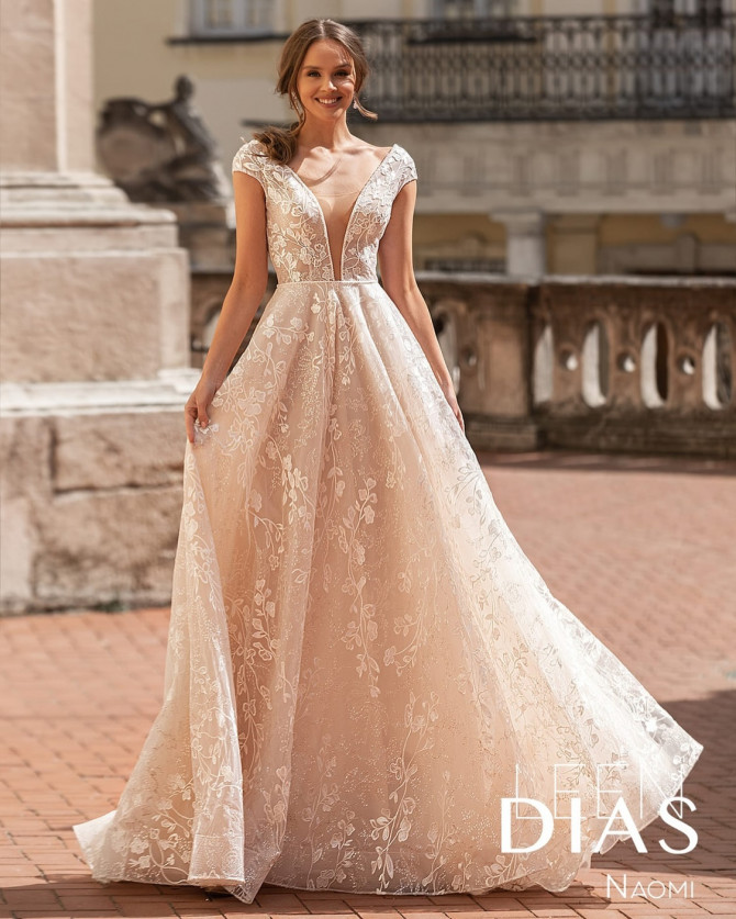Bride wearing a deep V-neck A-line wedding dress with cap sleeves and floral lace by Leen Dias