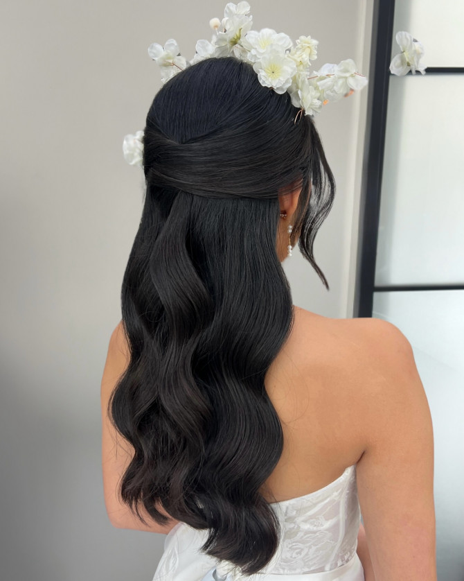 Romantic bridal half-up hairstyle with floral crown and glossy dark waves by @erikataftbridal. Half-up romantic bridal hairstyle with floral crown