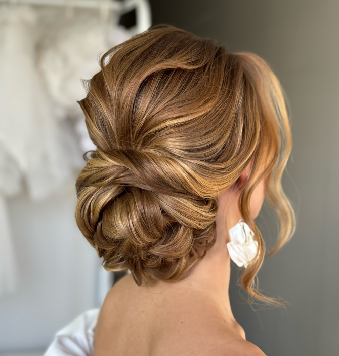  Elegant low bridal bun with romantic twists and soft face-framing waves by @valerypenteados