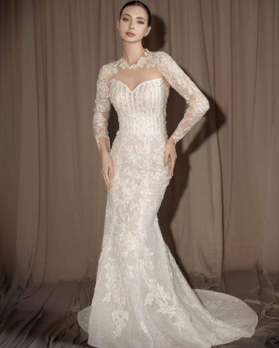 Bride in a long sleeve lace wedding dress with illusion neckline and fitted silhouette – Photo via IG @oddypranatha
