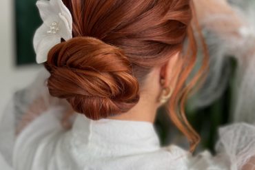 Sleek Cinnamon Low Bun with White Orchid Accent bridal hairstyle