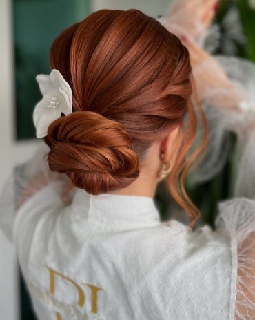 Sleek Cinnamon Low Bun with White Orchid Accent bridal hairstyle