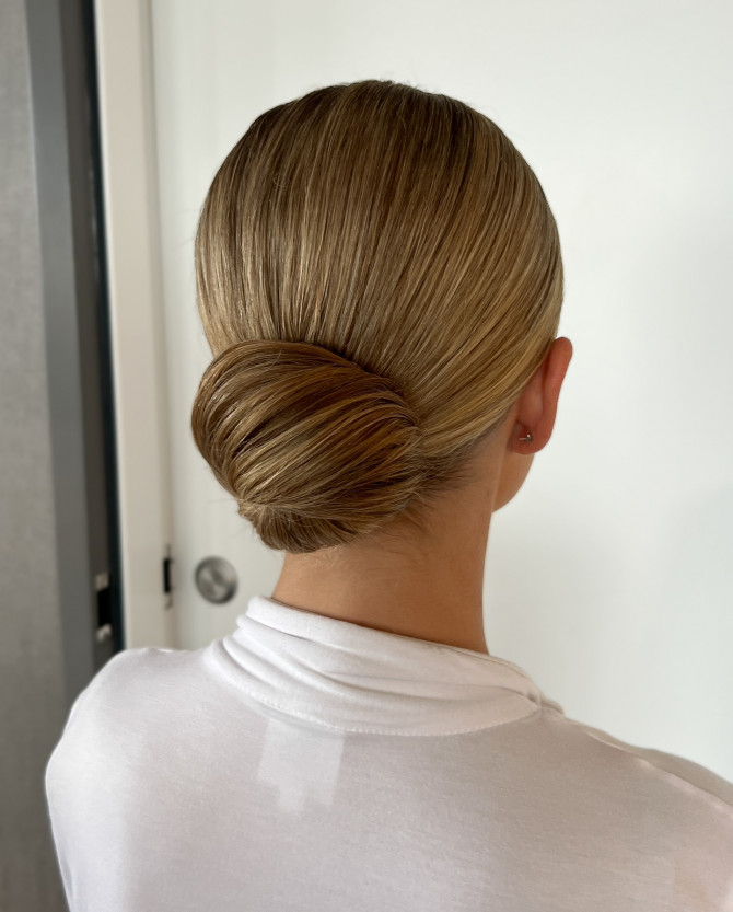 Sleek low bridal chignon with smooth finish and minimalist elegance by @erikataftbridal