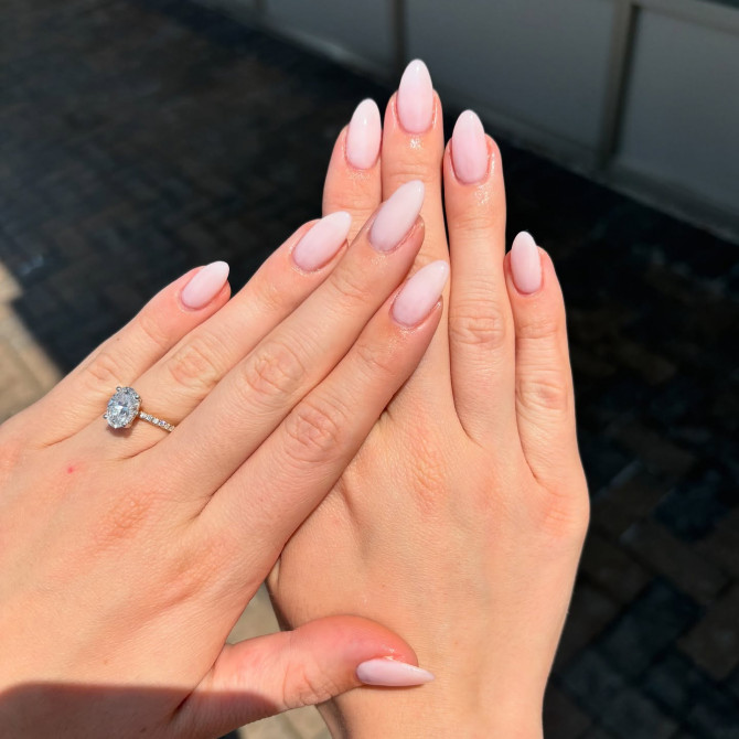 Elegant almond-shaped nails in a soft baby pink hue with a natural glossy finish—ideal for a timeless bridal manicure or engagement photo shoot. Elegant bridal nail designs with nude tones