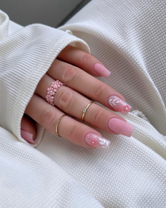 Elegant soft pink bridal nails with delicate white leaves and 3D pink flower accents, perfect for a romantic wedding look. Elegant bridal nail designs with nude tones
