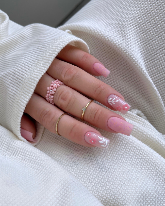 Elegant soft pink bridal nails with delicate white leaves and 3D pink flower accents, perfect for a romantic wedding look. Elegant bridal nail designs with nude tones