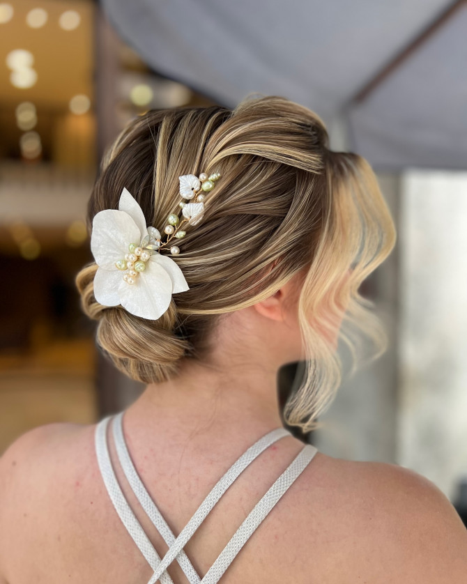 Soft low bridal bun with pearl orchid hair accessory and face-framing waves by @penteadoslucena