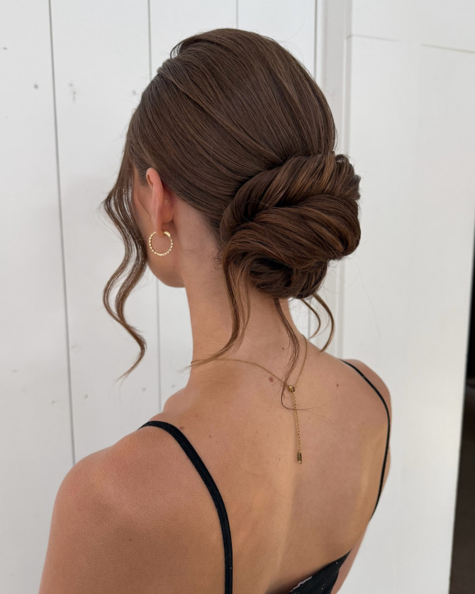 Elegant low bun bridal hairstyle with soft curls framing the face – minimalist wedding look by