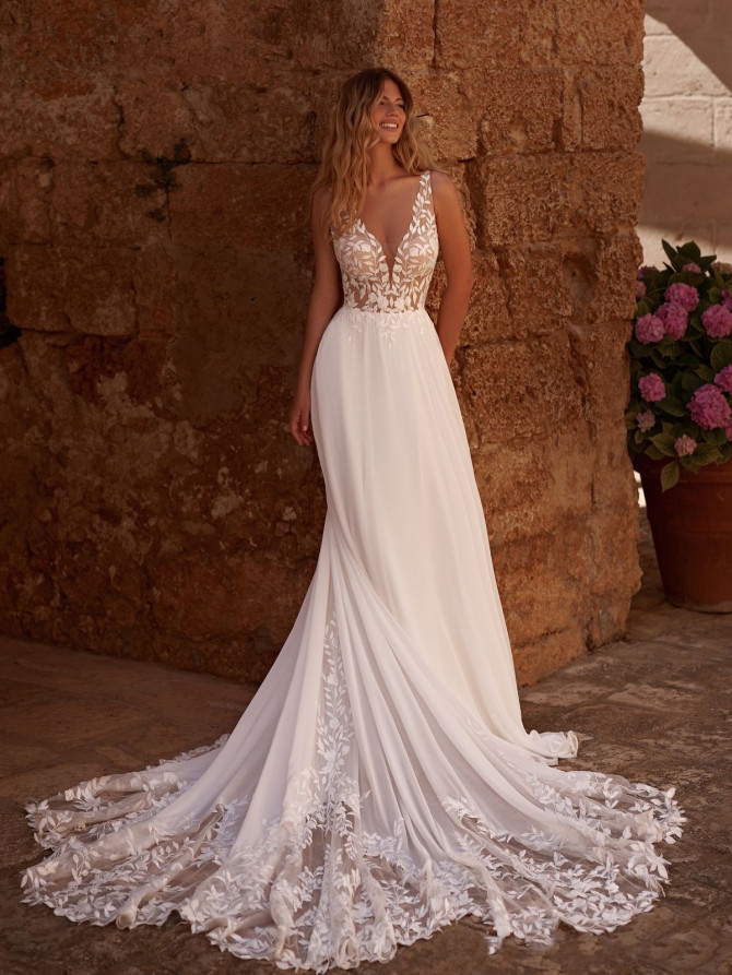 Bridal gown with dramatic layered skirt and fitted bodice. Elegant wedding gown from France