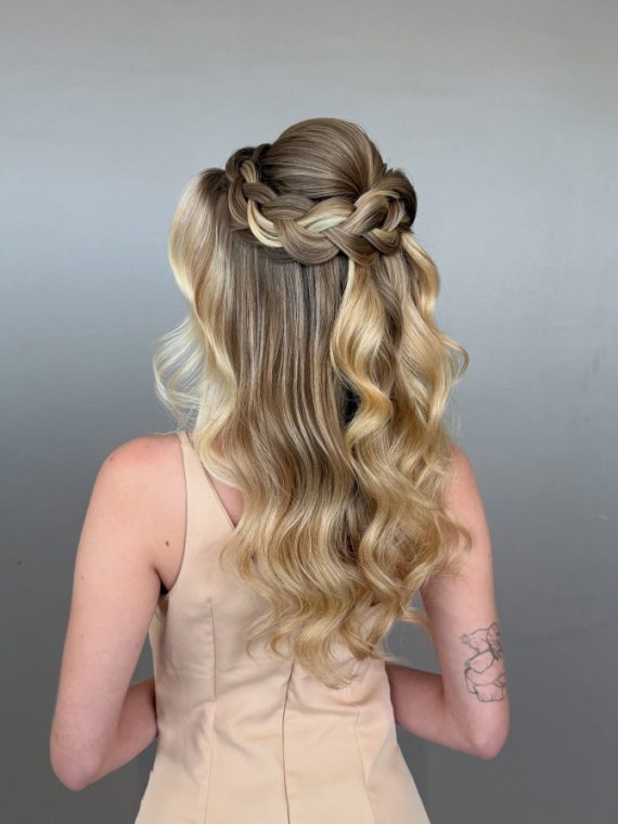 Braided crown half-up bridal style with soft waves.