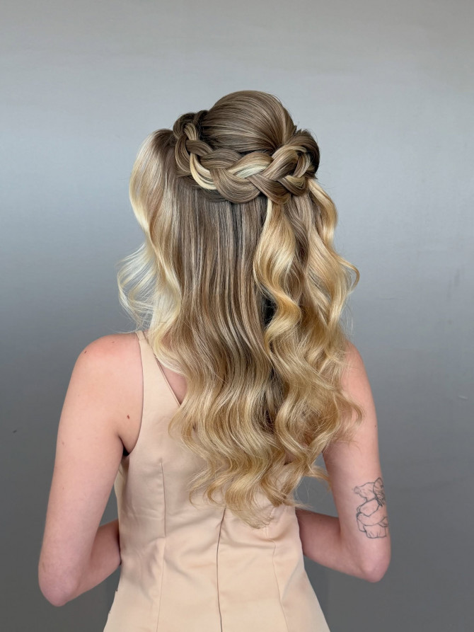 Braided crown half-up bridal style with soft waves.