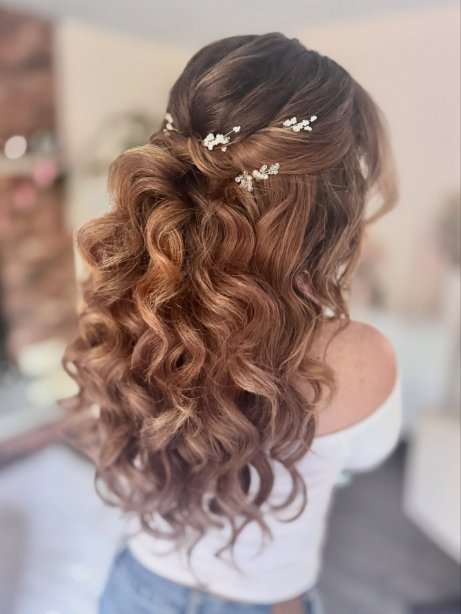 Half-up bridal hairstyle with romantic waves and pearl sprigs.