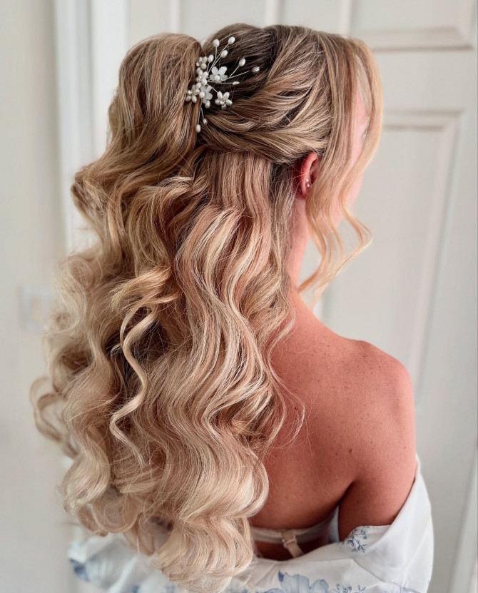 Half-up bridal hairstyle with long curls and pearl floral hair clip