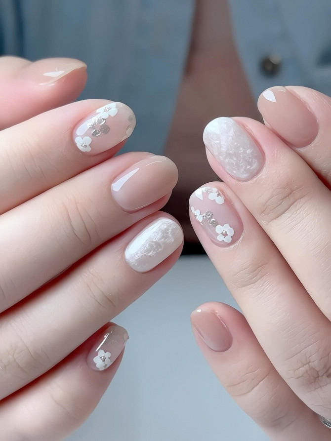 Milky nude nails with white floral overlays and shell texture accents Minimalist Blue Nails with Pearl Bow Tips