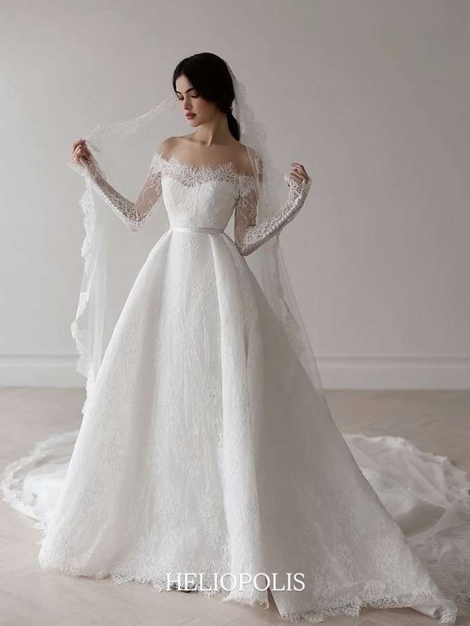 Off-shoulder lace A-line wedding dress with long sleeves, lace veil, and satin belt; classic romantic style. Satin one-shoulder A-line inspired by international bridal gowns; large rosettes in a gilded room