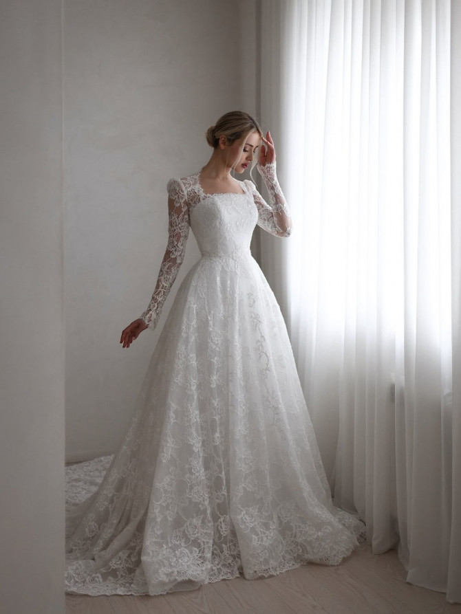 Square-neck long-sleeve lace A-line wedding gown with full skirt by a light-filled window. Strapless lace illusion A-line bridal gowns look with floral appliqués and light tulle skirt.”