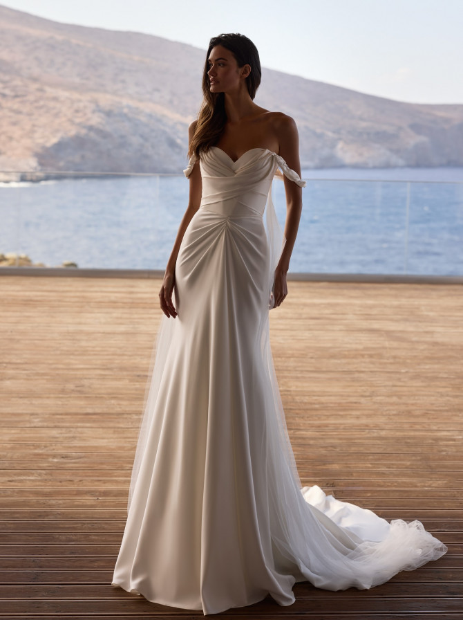  Tie-strap sweetheart sheath with soft ruching and tulle train; minimal bridal gowns feel by the sea.