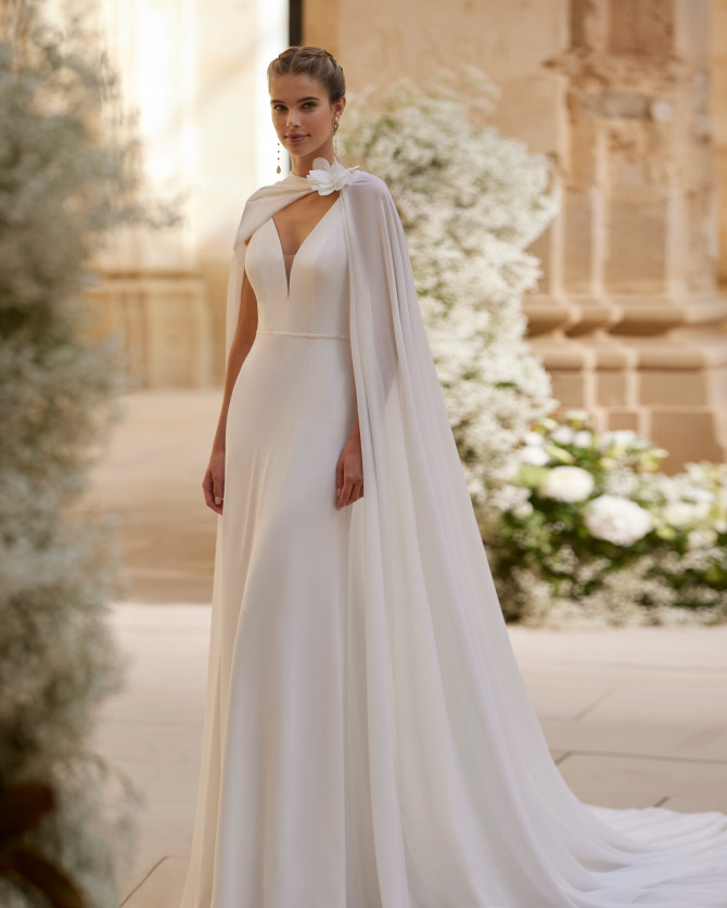 Minimal crepe column with floral shoulder capelet — international bridal gowns modern.